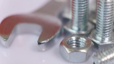 Dönüşümlü galvanize metal vidalar, ingiliz anahtarı ve fındık yakın çekim. Beyaz zemin üzerinde paslanmaz çelik cıvatalar izole.