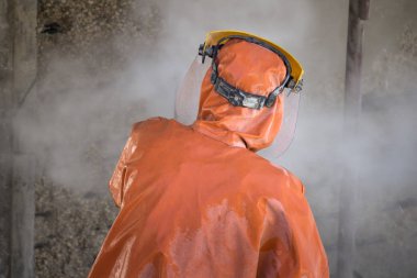 İşçi turuncu koruyucu kıyafetli korozyon hasarlı beton köprü ayağı yüksek basınçlı yıkayıcı ile temizler.