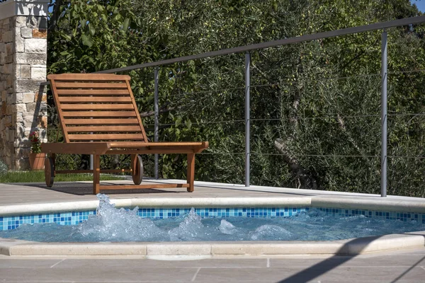 克罗地亚布拉克岛豪华公寓附近橄榄场泳池附近的木制甲板椅 图库图片