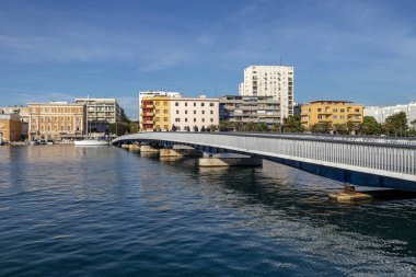 İnsanlar, Hırvatistan 'ın güneşli bir gününde Zadar kasabasında Jazine Körfezi 'ndeki şehir köprüsünü geçip