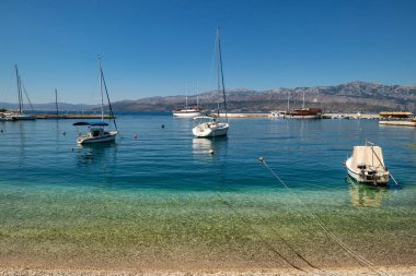 Hırvatistan 'ın Brac adasındaki Postira köyünün liman ve iskelesinde turist, balıkçı tekneleri ve deniz feneri bulunuyor. Turistik limanda sakin deniz yüzeyi.