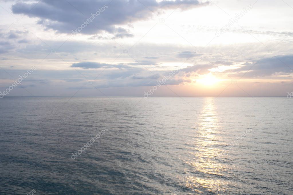 Pink sunrise on the sea beach. Sun reflection on the water.