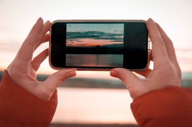 Dağ ve göl manzara fotoğrafını cep telefonuyla holding Womans eller.