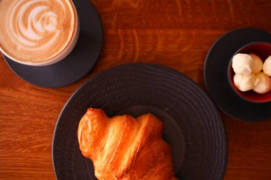 Beyaz kahve bardağı ve tereyağı ile siyah bir plaka üzerinde pişmiş kruvasanlar. Fırın Restoran yaşam tarzı.