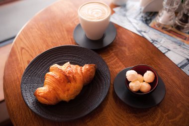 Beyaz kahve bardağı ve tereyağı ile siyah bir plaka üzerinde pişmiş kruvasanlar. Fırın Restoran yaşam tarzı.