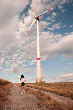 Yel değirmeni ile alanda yürüyüş çocuk.