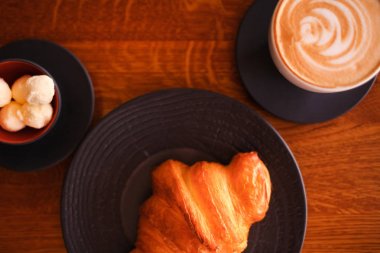 Beyaz kahve bardağı ve tereyağı ile siyah bir plaka üzerinde pişmiş kruvasanlar. Fırın Restoran yaşam tarzı.