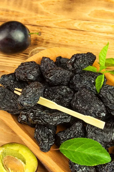 Prune, dried plums fruits on rustic wooden background. Dry plums in a wooden bowl. Healthy fruit