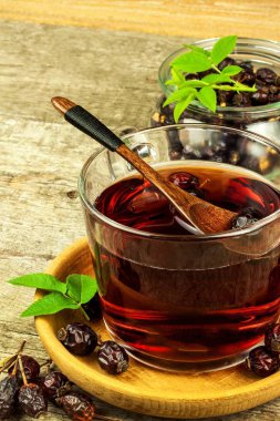 Ev yapımı Kuşburnu çayı. Soğuk algınlığı ve grip için geleneksel tedavi. Ahşap bir masa üzerinde kurutulmuş meyve. Sıcak Kuşburnu çayı. Kış çay.