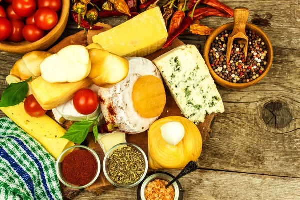 Various kinds of cheese served on wooden table. Wooden board with different kinds of delicious cheese on table. Sale of cheeses. Healthy food. Protein diet.