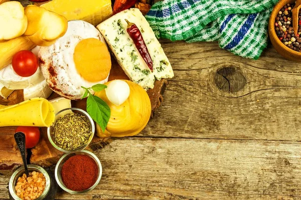 Various kinds of cheese served on wooden table. Wooden board with different kinds of delicious cheese on table. Sale of cheeses. Healthy food. Protein diet.