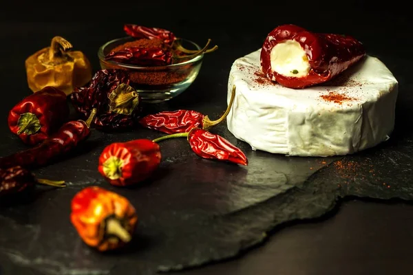 Moldy cheese and peppers on a black background. Dried chili peppers. Spicy moldy cheese. — Stock Photo, Image