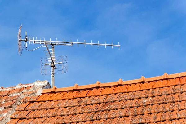 Old TV antenna on red roof. Receiving TV. Old technology communication. — Stock Photo, Image