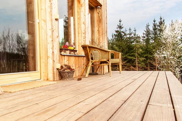 Wooden floor, Wooden terrace at an ecological house. Wicker chairs on a wooden terrace by the forest.