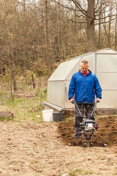 Solo de preparação de primavera para semeadura com perfilhos. Trabalho de primavera no jardim. Agricultor arado a terra com um cultivador, preparando-a para o plantio de legumes . — Fotografia de Stock