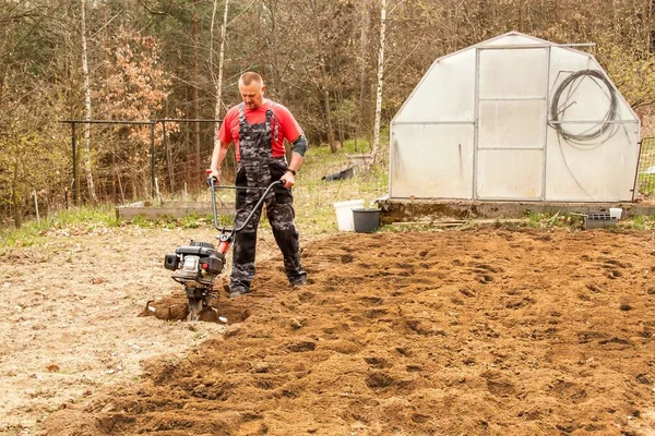 Solo de preparação de primavera para semeadura com perfilhos. Trabalho de primavera no jardim. Agricultor arado a terra com um cultivador, preparando-a para o plantio de legumes . — Fotografia de Stock