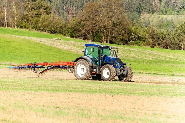 Blauwe trekker in het veld. Werken aan een landbouwbedrijf in de Tsjechische Republiek. Lente werk in de landbouw. — Stockfoto