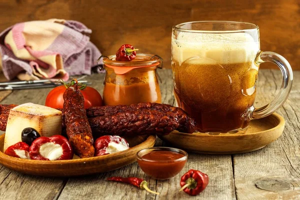 Dark beer in a glass and spicy sausages with chili peppers. Dried sausages on the table. — Stock Photo, Image