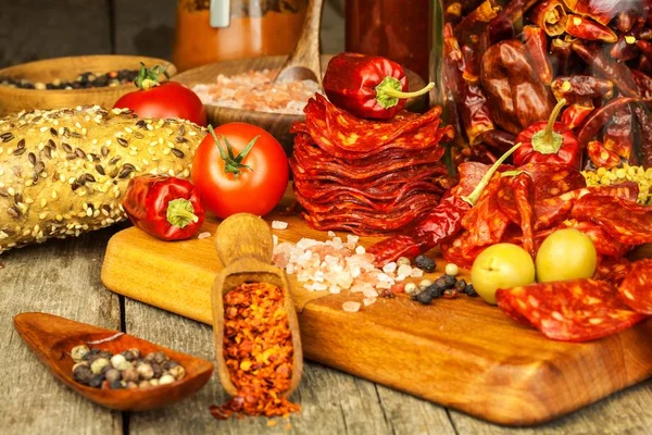 香肠或香肠与辣椒与香草在木桌上。辣香肠与辣椒。不健康的脂肪食品. — 图库照片