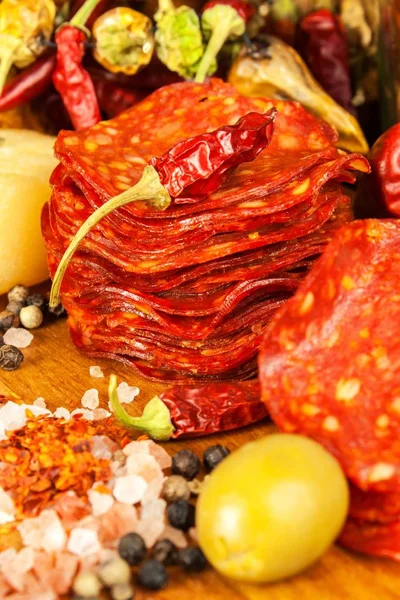 Korv eller salami med chilipeppar med örter på träbordet. Kryddig salami med chili. Ohälsosam fet mat. — Stockfoto