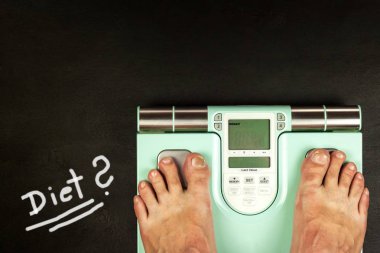 Obezite kavramı. Modern dijital ağırlık ve bacaklar. Diyette kilo kontrolü.