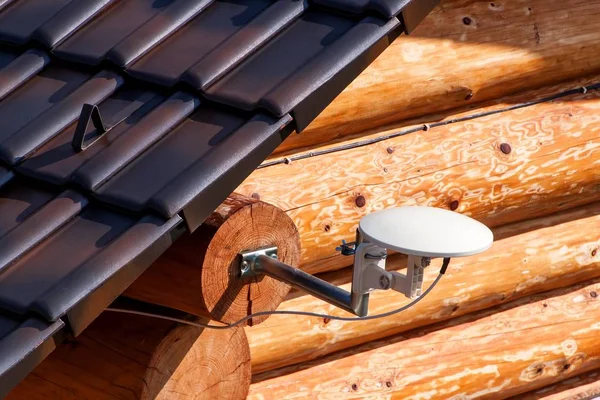 Antena de TV vía satélite en una casa de madera. Transmisión de señal de TV. Acceso a Internet. Medios de telecomunicaciones . — Foto de Stock