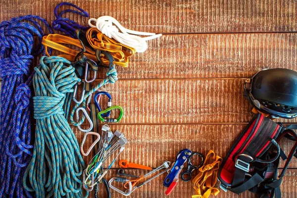 Climbing equipment for safe climbing sportsmen. Frame from safety equipment using in climbing, speleology, alpinism, over wooden background with copy space. — Stock Photo, Image