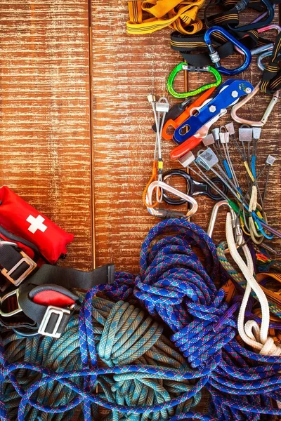 Equipo de escalada para deportistas de escalada seguros. Marco del equipo de seguridad que utiliza en escalada, espeleología, alpinismo, sobre fondo de madera con espacio de copia . — Foto de Stock