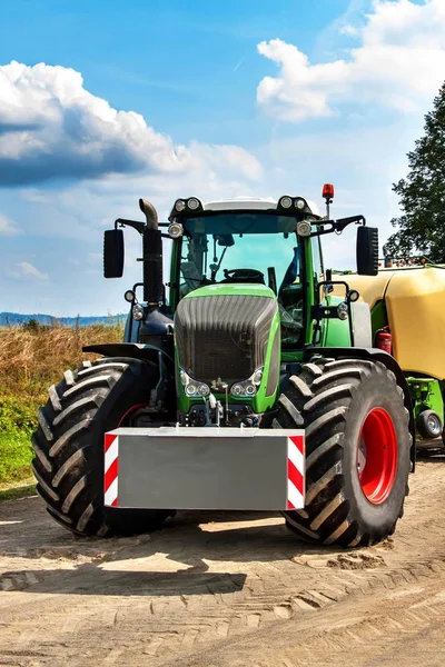 Power traktor hijau modern di lapangan. Langit biru dengan awan. Mesin pertanian modern. Bekerja di peternakan . — Stok Foto