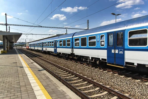 Tren en plataforma en la estación en la República Checa. Vías férreas con traviesas de hormigón. Estación ferroviaria local . — Foto de Stock