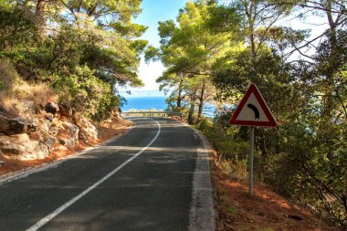 Road above the sea on the Croatian island of Lastovo. Road transport. Morning sun on the road by the sea. Asphalt road.