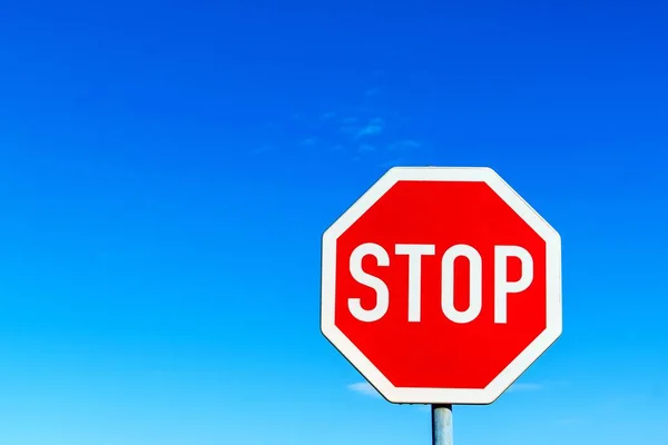 Na modré obloze zastavte silniční nápis. Výstražný symbol. Povinnost zastavit. Varování před nebezpečím. — Stock fotografie