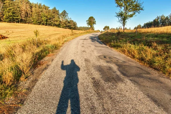 Ombre masculine sur la route. Soleil du matin sur route asphaltée. Le matin d'été. Route de campagne le matin . — Photo