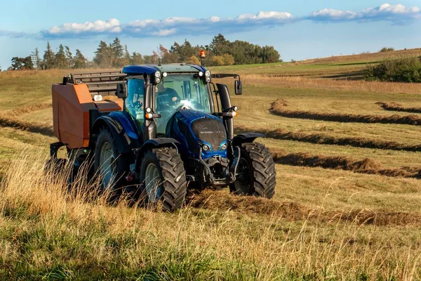 Blue traktor kemasan jerami. Pekerjaan musim gugur di peternakan. Traktor di lapangan. Ekologi pertanian . — Stok Foto