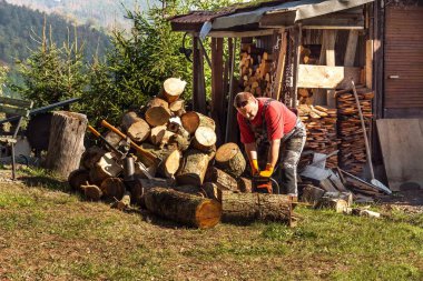 Adam elektrikli testereyle kesiyor. Kış için odun hazırlıyorum. İşçi odun keser. Ekolojik ısıtma.