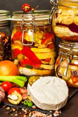 Kırmızı soğanlı turşulu peynir. Ev yapımı peynir turşusu. Yemek turşusu. Camembert peynirli kavanoz. Siyah ahşap masada yağda marine edilmiş..