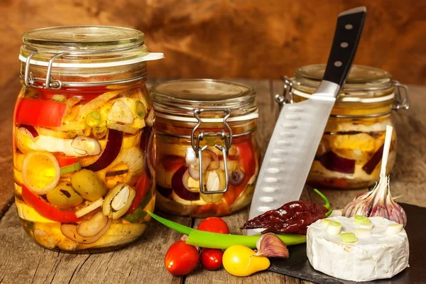 Cheese pickled in olive oil. Home-made pickled cheese. Jar with Camembert cheese marinated in oil on wooden table. — Stock Photo, Image