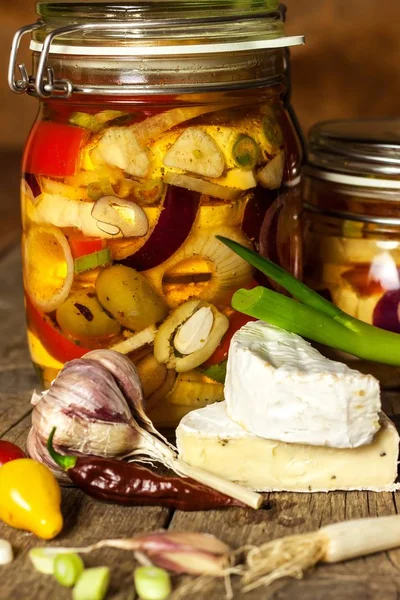 Cheese pickled in olive oil. Home-made pickled cheese. Jar with Camembert cheese marinated in oil on wooden table. — Stock Photo, Image