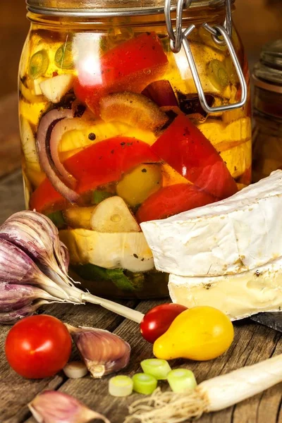 Cheese pickled in olive oil. Home-made pickled cheese. Jar with Camembert cheese marinated in oil on wooden table. — Stock Photo, Image