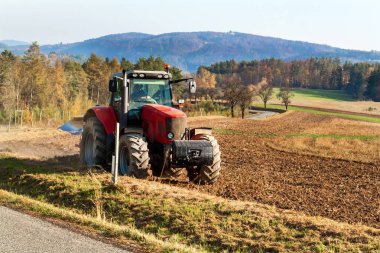 Kırmızı traktör tarlayı sürüyor. Çek Cumhuriyeti 'nde bir çiftlikte çiftlik işi. Sonbahar manzarası.