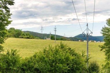 Yazın mavi gökyüzüne karşı kırsal kesimde elektrik hatları. Çek kırsal kesiminin manzarası. Enerji dağılımı.