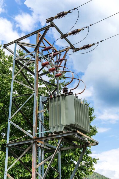 Energy and technology: electric pole by the road with power lines cables, transformer against the blue sky. Environmental concept. Electricity distribution.