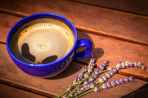 Cup of hot coffee and lavender on a wooden table. Aroma of coffee and lavender. Romantic morning.