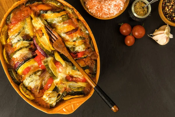 ratatouille vegetarian dish, baked vegetables. Diet vegetable food. Traditional french baked ratatouille on black background.