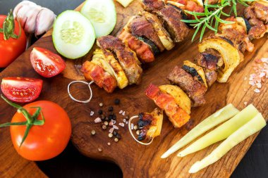 Kebap - ızgara et ve sebze. Tahta kesme tahtasının üzerinde domuz şişi. Siyah arka planda taze bir barbekü. Yaz barbeküsü.