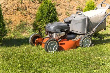 Bahçıvanlık. Benzin çim biçme makinesiyle çim biçmek, tekerleğin üzerine yakın plan çekmek. Çim biçme. Benzin motoru.