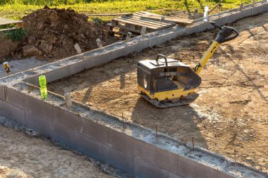 Titreşimli plaka sıkıştırıcısı yapım aşamasında. İnşaat alanında titreşimli plaka sıkıştırıcısı. İnşaat malzemeleri. Yumuşak sıkıştırma aracı