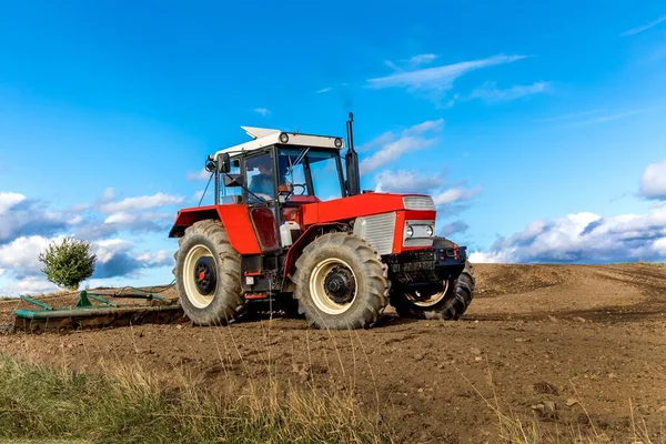 Rolnictwo Czerwony Traktor Kultywuje Pole Nad Błękitnym Niebem Stary Czerwony — Zdjęcie stockowe