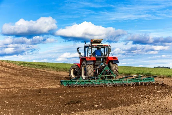 农业用红色拖拉机在蓝天上耕地 农田里的旧红色拖拉机 机械装置 拖拉机犁地 播种机播种小麦 — 图库照片