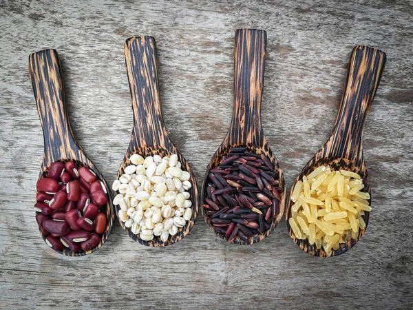 seed on wood spoon / grains or cereals seeds on wooden spoon various kinds of grains with red kidney bean , Job\'s tears , riceberry and brown rice on wooden background